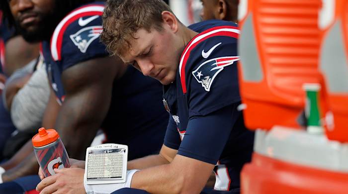 Patriots quarterback Mac Jones, right, is seated on the bench after he was pulled during the second half against the Saints.